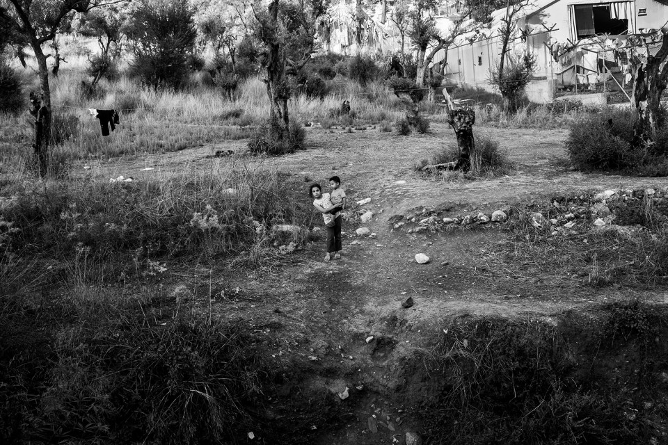 A young girl carrying her little brother just outside camp Moria, Lesbos, Greece