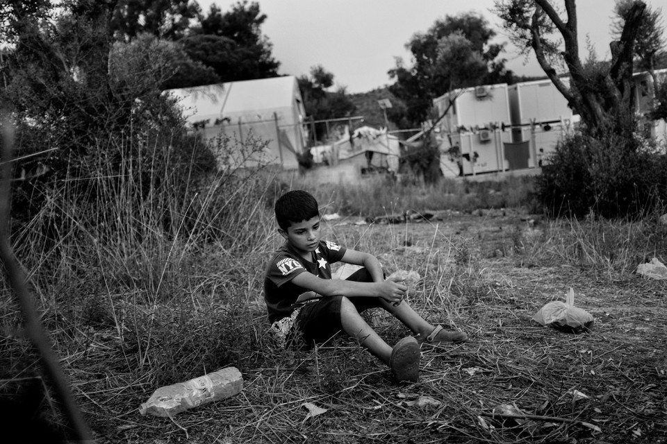 A Syrian young boy who came with his parents and 2 sisters just outside the back of the refugee camp Moria where they prepare their dinner on a wood fire. Lesbos, Greece A Syrian young boy who came with his parents and 2 sisters just outside the back of the refugee camp Moria where they prepare their dinner on a wood fire. Lesbos, Greece