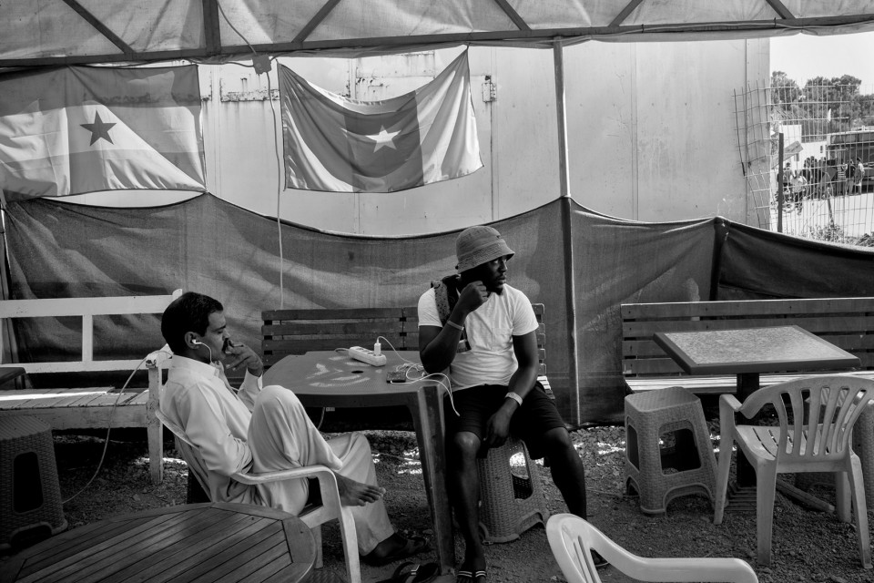 Refugees at a cafe next to the camp Moria where the owner hanged African flags, Lesbos, Greece