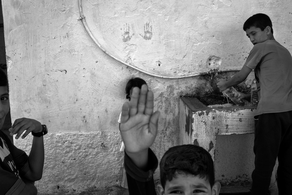 Children at a watertapinside the refugee camp Moria, Lesbos, Greece